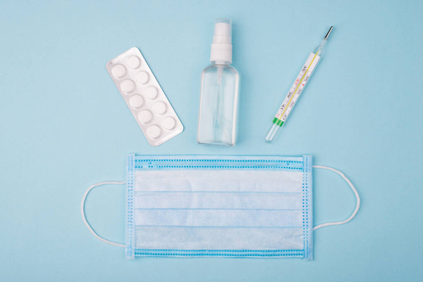 Hygiene and self prevention concept. Top above overhead close up view photo of bottle with liquid thermometer tablets and medical mask isolated over background - Zdjęcie, obraz