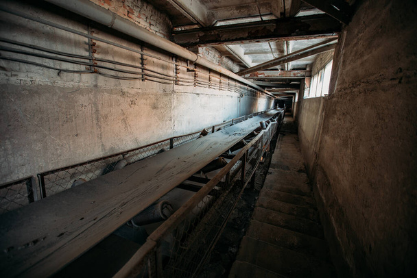 Abandoned cement and concrete factory. Old rusty conveyor in corridor. - Fotó, kép