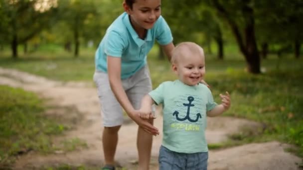 かわいい兄弟たちが公園を歩いている。兄helジュニアへ作るためにステップ屋外 - 映像、動画