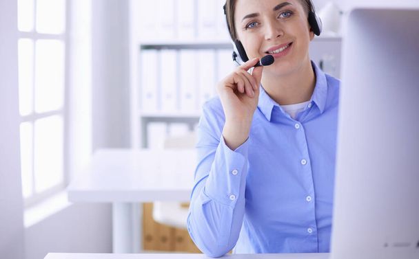 Serious pretty young woman working as support phone operator with headset in office - Фото, изображение