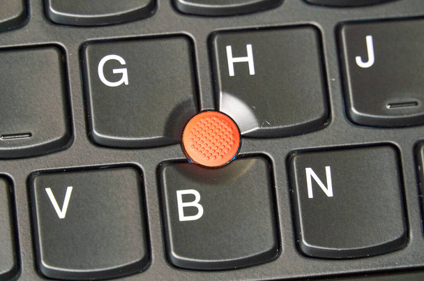 Punto de seguimiento rojo en un teclado portátil. Un palillo de apuntar es un pequeño joystick utilizado como un dispositivo de apuntar normalmente montado centralmente en un teclado de computadora
. - Foto, imagen