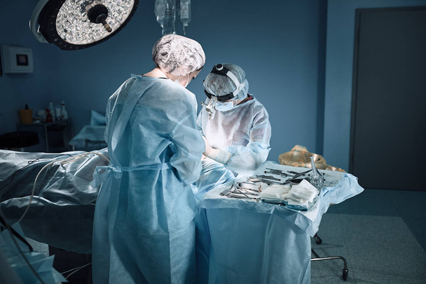 W szpitalnej sali operacyjnej. Międzynarodowy zespół profesjonalnych chirurgów i asystentów pracuje w nowoczesnej sali operacyjnej. Profesjonalni lekarze świętują uratowanie życia. - Zdjęcie, obraz