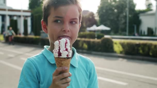 Zárd be az ocute boy eszik jégkrémet. Nyugodt gyermek sétál a vidámparkban - Felvétel, videó
