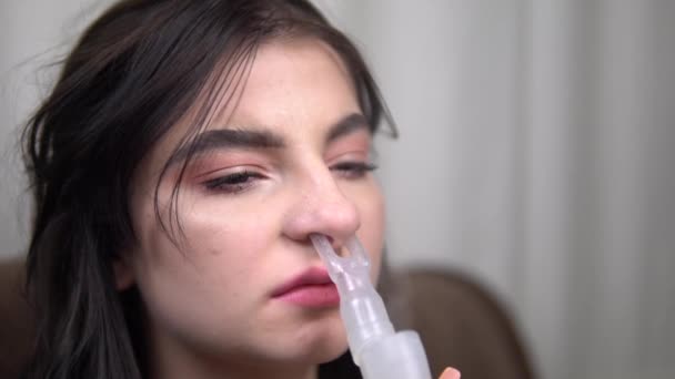 Genç bir kadın burun için astım spreyinden nefes alıyor. Yakın çekim nebulizör. Yavaş motivasyon - Video, Çekim