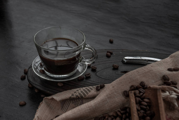 Kávé stílus, csésze kávé és kávébab roating régi fa kanál és kávébab körül a fa és a sötét kő háttér. Felülről ferde nézet a tetejről másolóhellyel a szövegben. - Fotó, kép