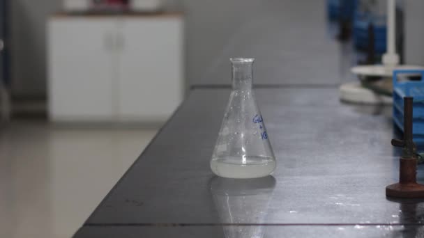 cambio de color de una sustancia química blanca en un matraz cónico al añadir una sustancia química blanca de un matraz cónico en un laboratorio de química
 - Metraje, vídeo