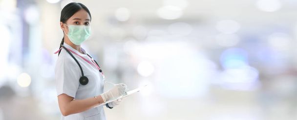Widok boczny kobiety lekarza piszącej kartę pacjenta na tablecie cyfrowym w niewyraźnym tle szpitala - Zdjęcie, obraz