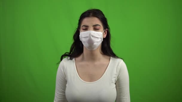 Girl in mask coughs on a green screen. The girl caught the virus. Coronavirus - Кадры, видео