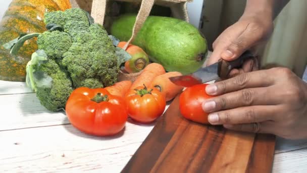 zbliżenie człowieka ręka cięcia pomidora na desce do siekania  - Materiał filmowy, wideo