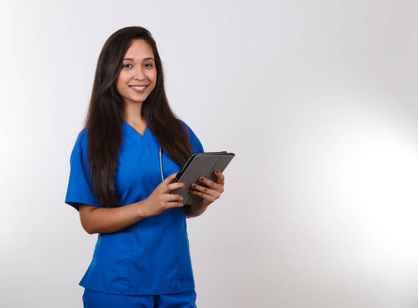 An attractive female nurse takes notes on her tablet. - Φωτογραφία, εικόνα