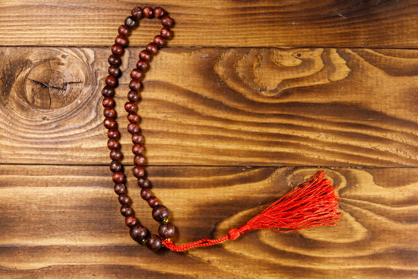 Wooden rosary on wooden background. Top view, copy space - Photo, image