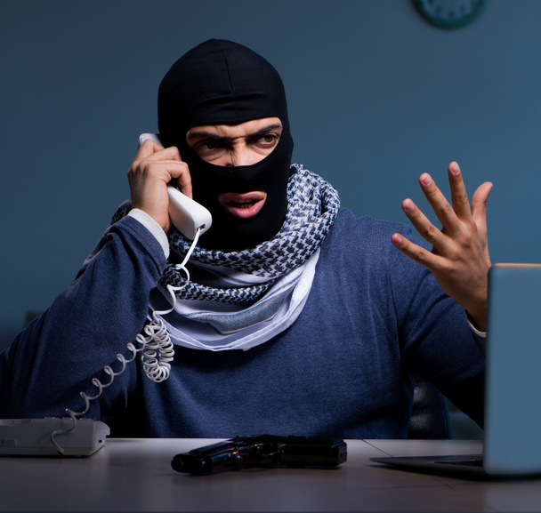 Ladrón terrorista con pistola trabajando en la computadora - Foto, Imagen