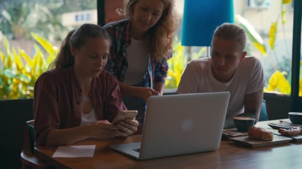 Equipo de jóvenes compañeros de trabajo trabajando en computadoras portátiles y discutiendo negocios
 - Metraje, vídeo