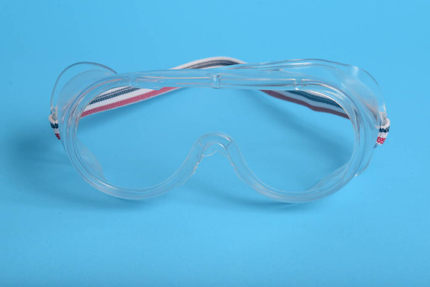transparent plastic laboratory glasses on blue background - Photo, Image