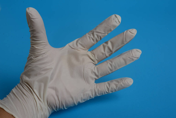 Handschuh-Latex-Handprüfung auf blauem Hintergrund - Foto, Bild