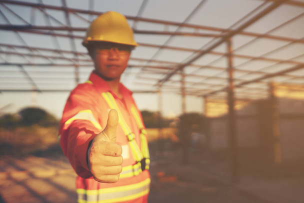 Engenheiro usar um capacete duro e mostrar o polegar no local de construção
 - Foto, Imagem