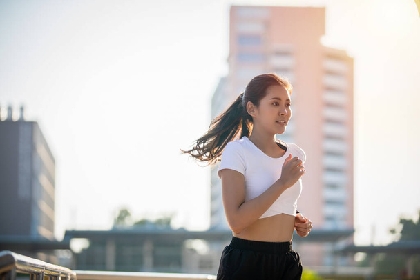 Asiática joven fitness deporte mujer corriendo y sonriendo en la ciudad carretera
 - Foto, imagen