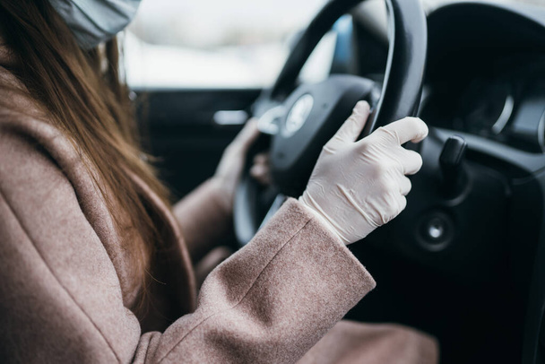 Giovane donna in maschera e guanti alla guida di una macchina. - Foto, immagini