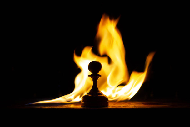 tabuleiro de xadrez em chamas com figuras no escuro, frente e fundo borrado com efeito bokeh
 - Foto, Imagem