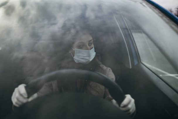 Mladá žena v masce a rukavicích řízení auta. - Fotografie, Obrázek