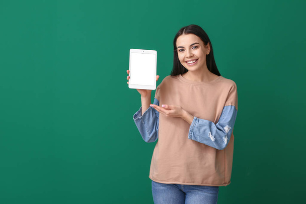Beautiful young woman with tablet computer on color background - Foto, immagini