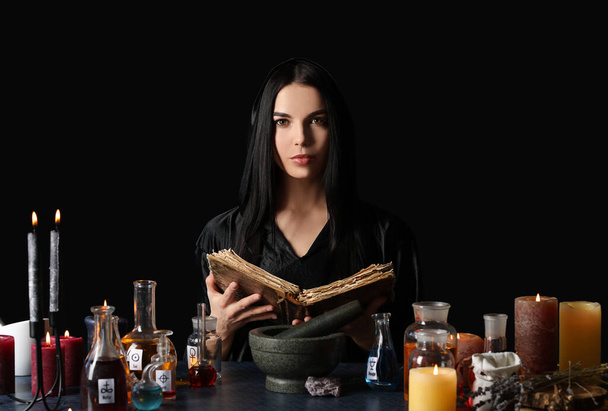 Female alchemist making potion on dark background - Photo, Image