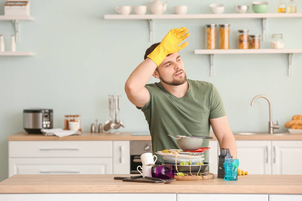 Zmęczony człowiek z brudnymi naczyniami w kuchni - Zdjęcie, obraz
