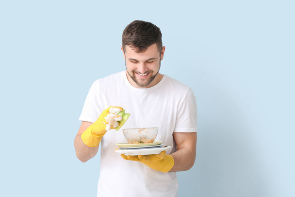 Mann mit schmutzigem Geschirr auf farbigem Hintergrund - Foto, Bild