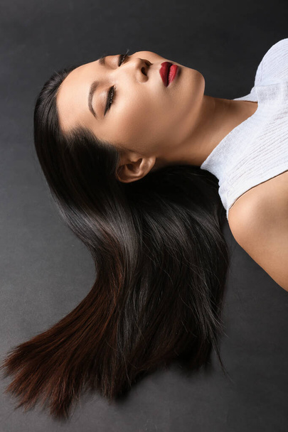 Young Asian woman with beautiful hair on dark background - Φωτογραφία, εικόνα