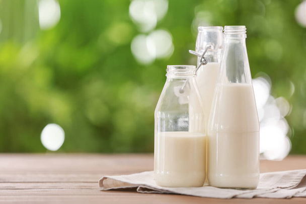Пляшки свіжого молока на столі на відкритому повітрі
 - Фото, зображення