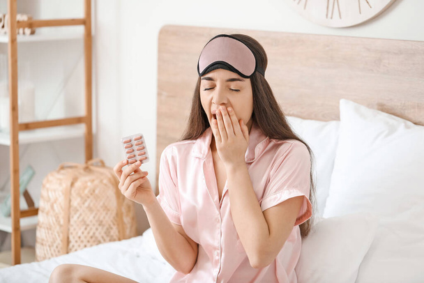 Fáradt nő gyógyszerekkel álmatlanság a hálószobában - Fotó, kép