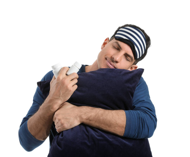 Młody człowiek z tabletkami nasennymi i poduszką na białym tle - Zdjęcie, obraz
