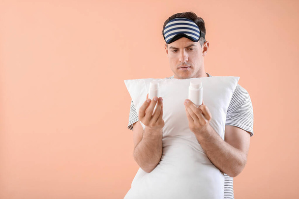 Young man with sleeping pills and pillow on color background - Φωτογραφία, εικόνα