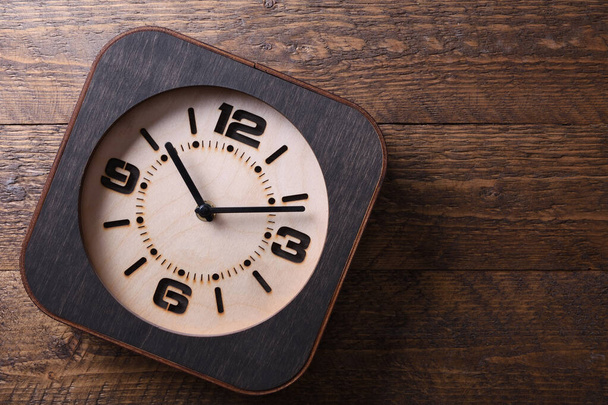 Reloj de madera hecho a mano sobre fondo de madera. Primer plano. Lugar para un texto. - Foto, Imagen