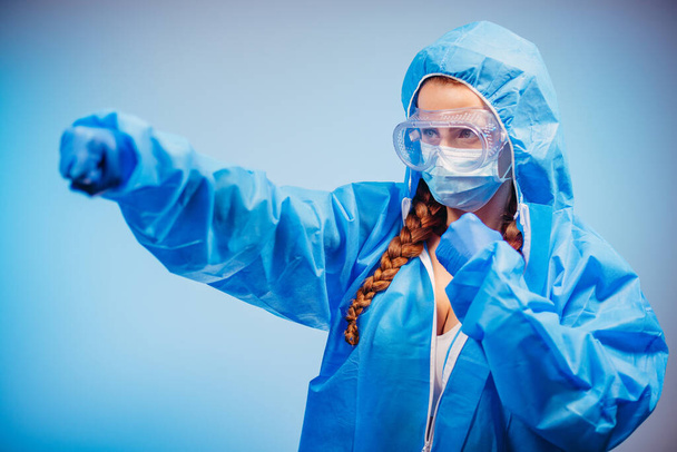 Virus. A woman in a protective anti-virus suit fists in the air. - Foto, Bild