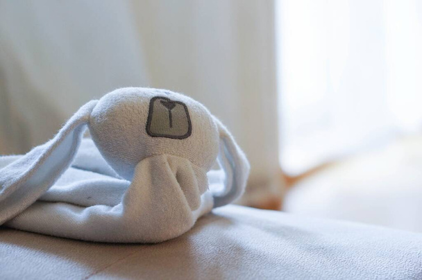 A soft focus of a soft plush white rabbit towel on a bed - Фото, зображення