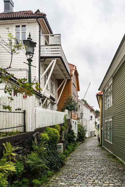 A vertical shot of a narrow cozy street with typical wooden houses in Bergen, Norway - Zdjęcie, obraz