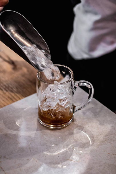 A vertical closeup shot of ice cubes being poured into the glass - Zdjęcie, obraz
