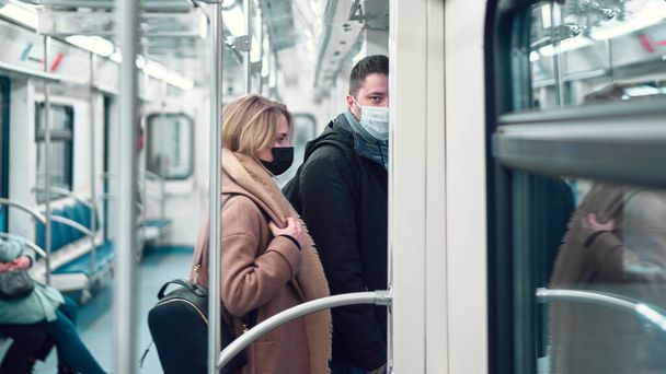 Man and woman in medical masks standing in subway carriage. - Foto, Imagem