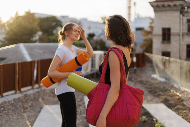 Two young beautiful women in sportswear going to do sports training, gymnastics, yoga. Healthy sports lifestyle concept. Women friendship - 写真・画像