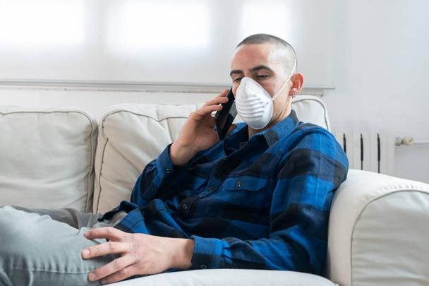 Coronavirus. Man at home wearing protective mask. Woman in quarantine for coronavirus on the couch cleaning her hands with sanitizer gel. Working from home. Clean your hands with sanitizer gel.  - Zdjęcie, obraz