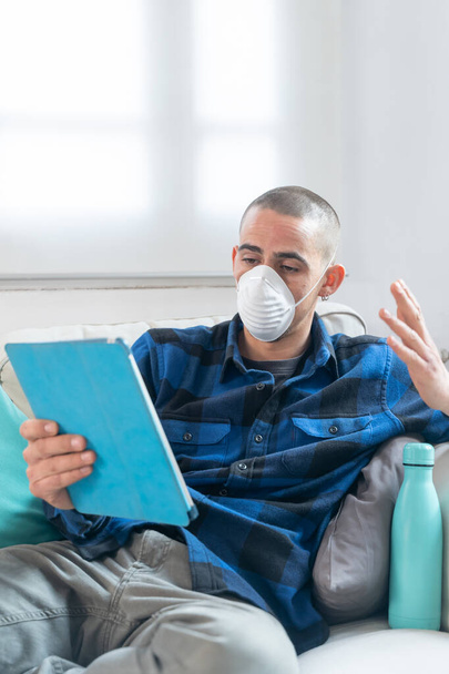 Coronavirus. Woman at home wearing protective mask. Woman in quarantine for coronavirus on the couch cleaning her hands with sanitizer gel. Working from home. Clean your hands with sanitizer gel.  - Φωτογραφία, εικόνα