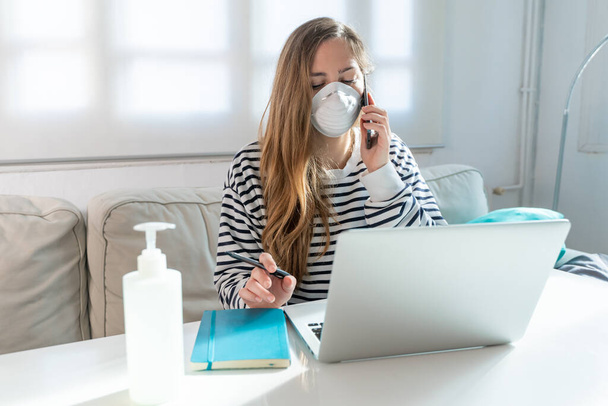 Coronavirus. Woman at home wearing protective mask. Woman in quarantine for coronavirus on the couch cleaning her hands with sanitizer gel. Working from home. Clean your hands with sanitizer gel.  - Foto, afbeelding