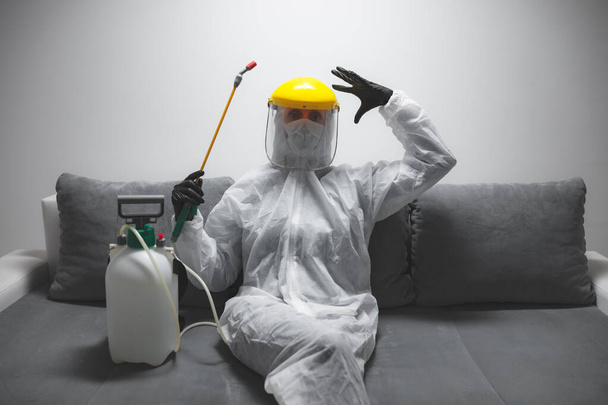 Pessoa com máscara antiviral protetora, frasco pulverizador de descontaminação química em isolamento caseiro
. - Foto, Imagem