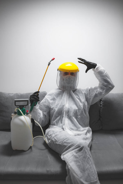 Person mit antiviraler Schutzmaske, Sprühflasche zur chemischen Dekontamination in der Isolation zu Hause. - Foto, Bild
