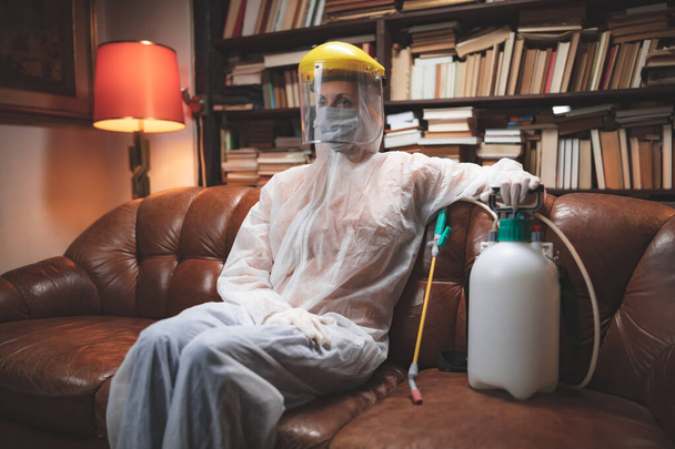 Osoba z ochronną maską przeciwwirusową, chemicznym rozpylaczem w izolacji domowej. - Zdjęcie, obraz