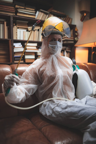 Osoba z ochronną maską przeciwwirusową, chemicznym rozpylaczem w izolacji domowej. - Zdjęcie, obraz