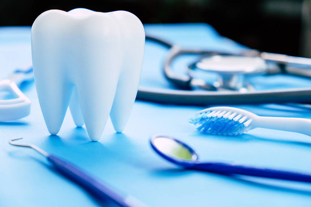 Mavi arka planda diş modeli ve dişçi ekipmanı, diş arka planının konsept görüntüsü. Diş temizliği geçmişi - Fotoğraf, Görsel