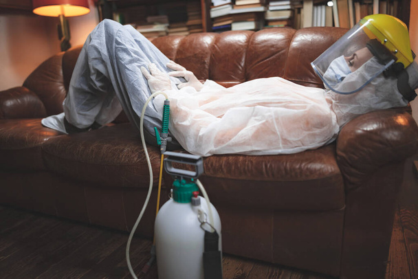 Person with protective antiviral mask, chemical decontamination sprayer bottle in home isolation. - Foto, immagini