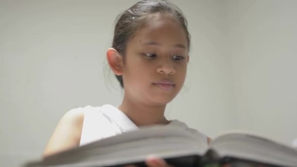 Kütüphanede kitap okuyan, beyaz gömlekli, sevimli, gülümseyen genç bir kız. Güzel bayan genç, kitaplardan faydalı bilgiler ve bilgiler edinmeyi sever. Eğitim kavramı. - Video, Çekim